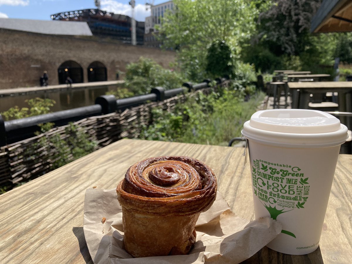 A cinnamon roll and a coffee cup on a table Description automatically generated