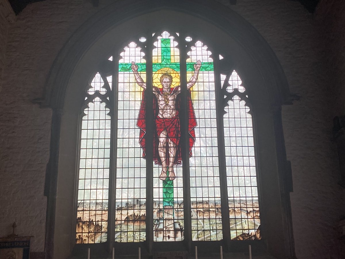 A stained glass window with a person on the cross Description automatically generated